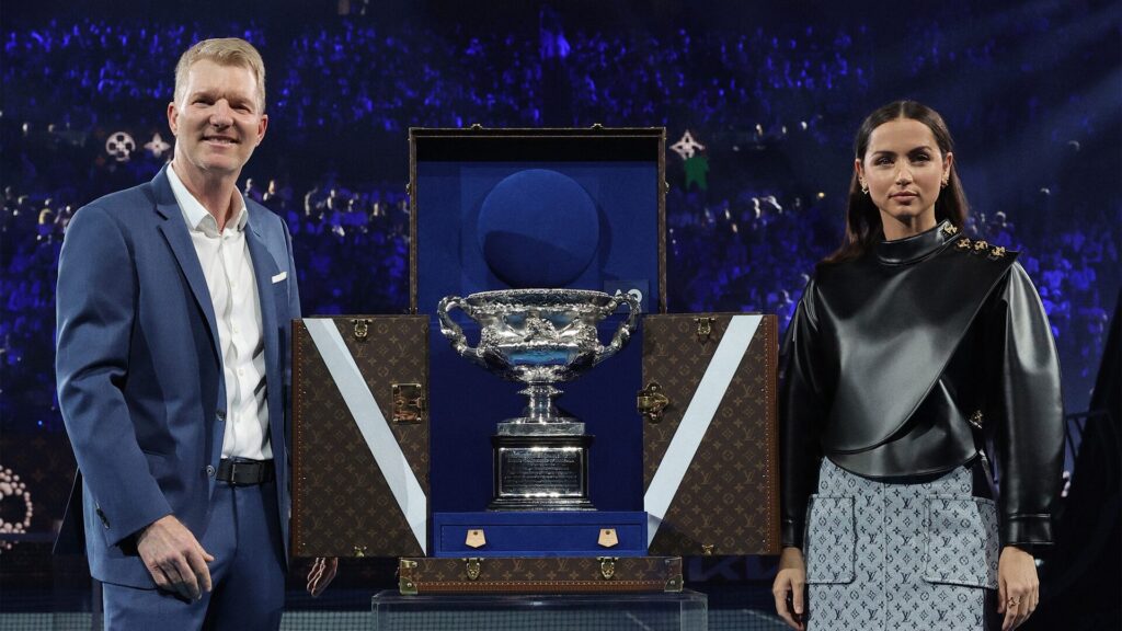 【ルイ・ヴィトン】アナ・デ・アルマスとジム・クーリエ、全豪オープンの男子決勝において、ルイ・ヴィトンのトロフィー・トランクに収められたトロフィーを披露